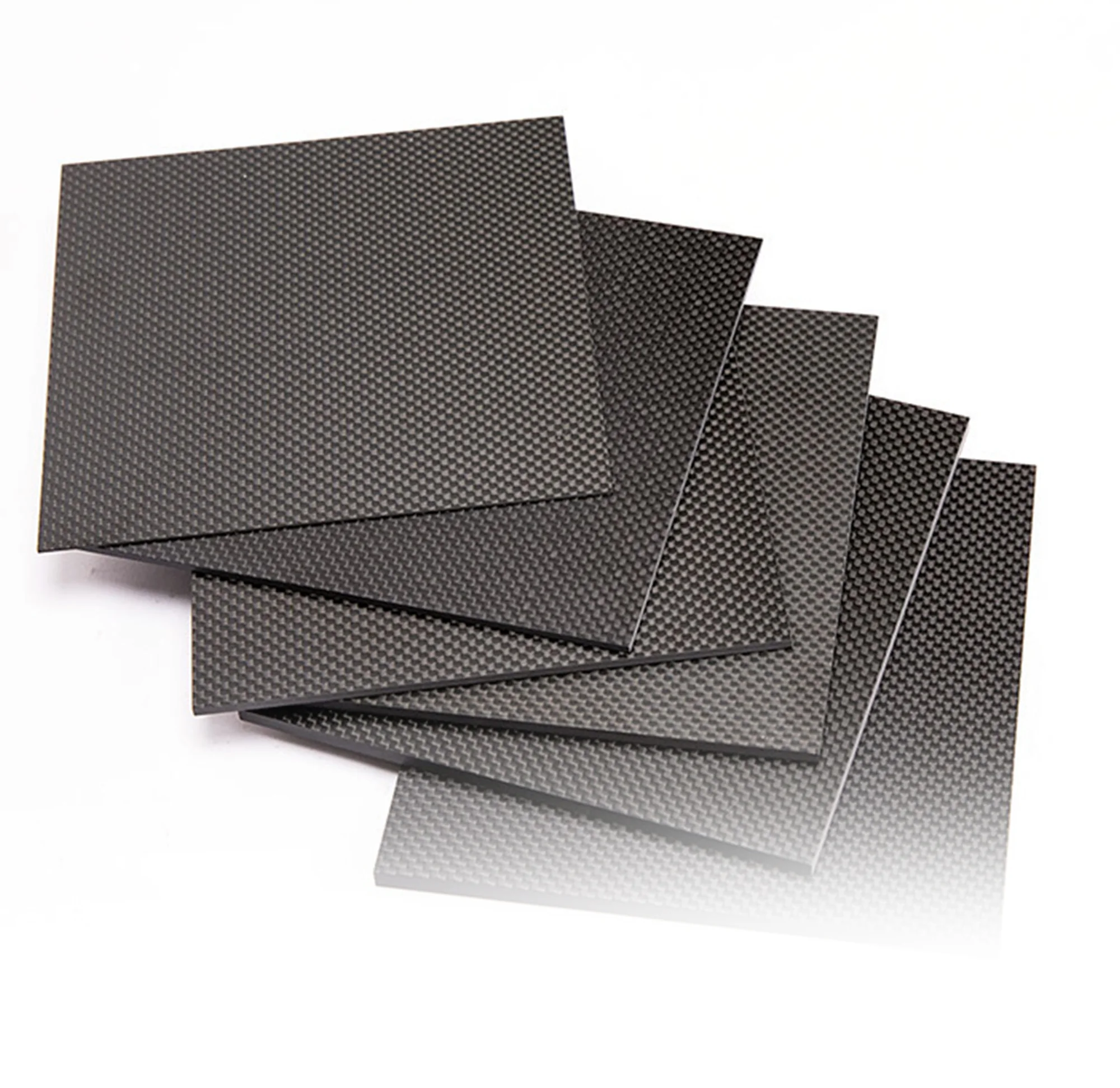Stack of dark carbon-fiber laminate sheet blanks on a light surface